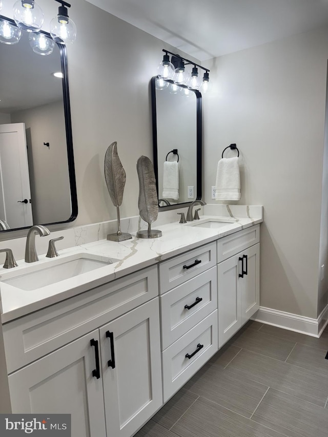 full bath featuring a sink, baseboards, and double vanity