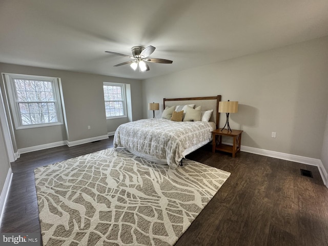 bedroom featuring ceiling fan, visible vents, baseboards, and dark wood-style floors