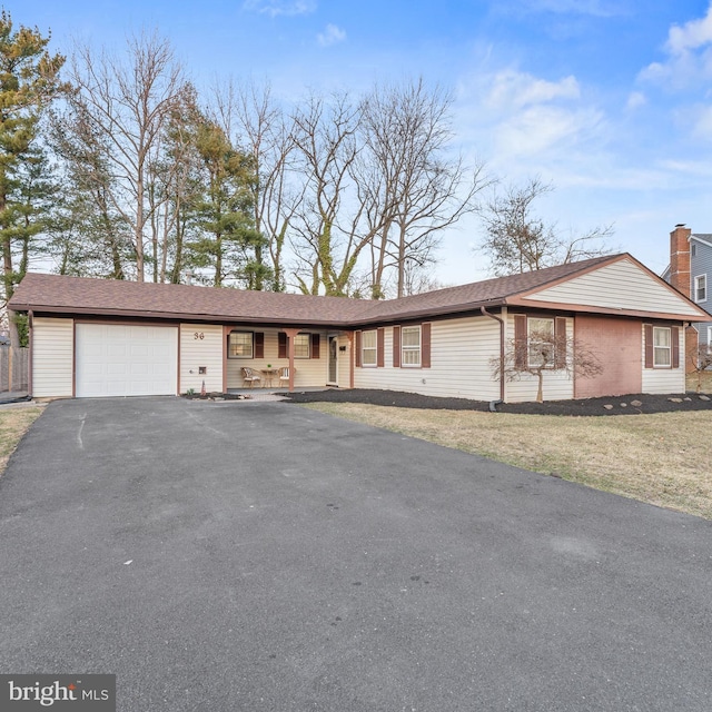 single story home featuring a front yard, a garage, and driveway