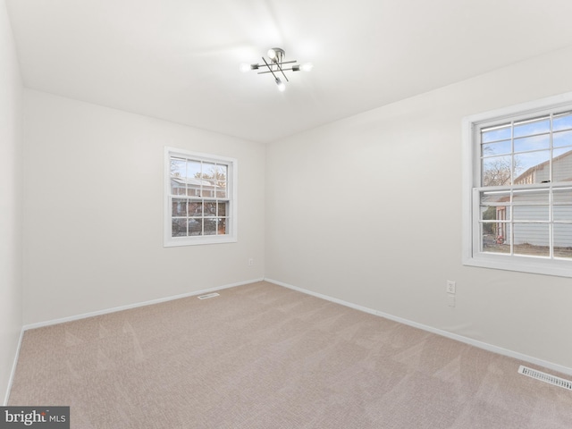 unfurnished room featuring baseboards, visible vents, a wealth of natural light, and carpet floors