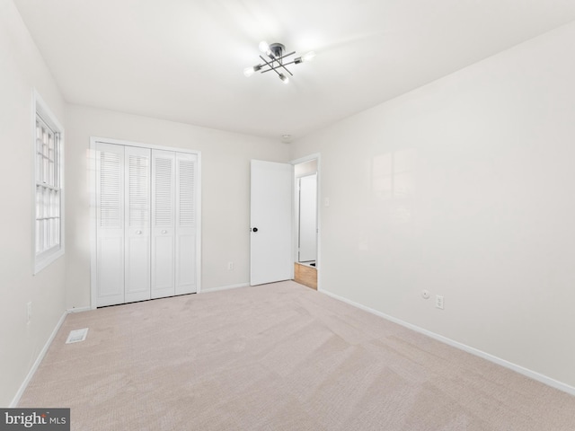 unfurnished bedroom with a closet, visible vents, baseboards, and carpet floors