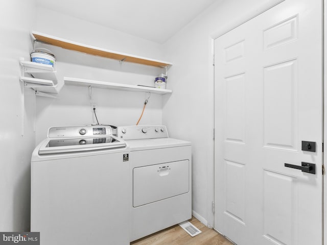 laundry area with light wood finished floors, laundry area, and separate washer and dryer