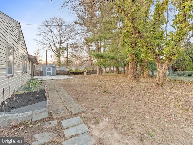 view of yard with an outbuilding, a garden, a storage unit, and fence