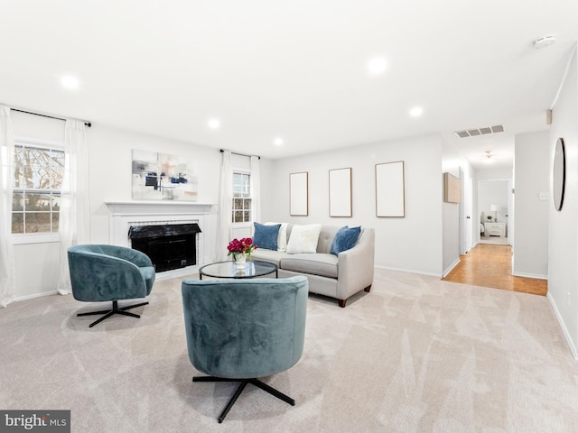 living room with recessed lighting, a fireplace, visible vents, and light carpet