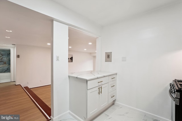 kitchen featuring range with gas stovetop, light stone countertops, baseboards, recessed lighting, and white cabinets