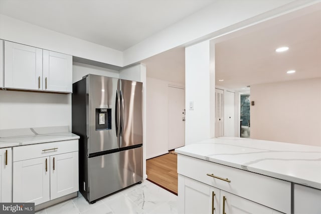 kitchen with marble finish floor, white cabinetry, recessed lighting, stainless steel fridge, and light stone countertops