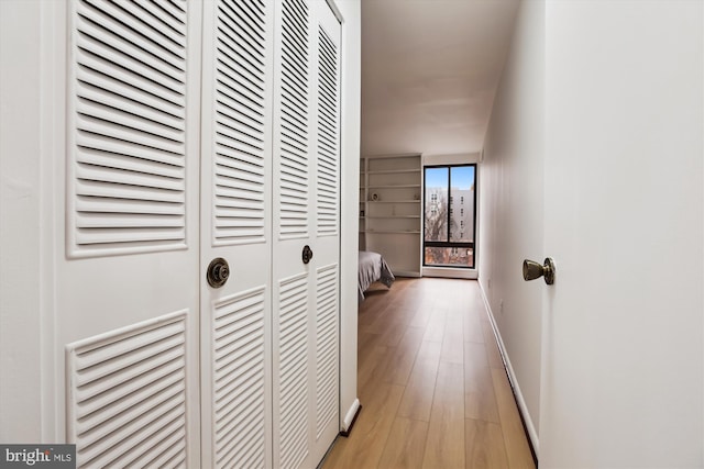 corridor with baseboards and light wood finished floors