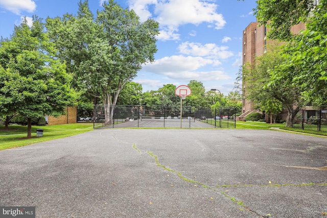 view of basketball court with community basketball court, a lawn, and fence