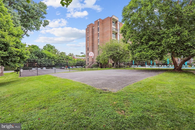 view of property's community featuring a tennis court, a lawn, community basketball court, and fence