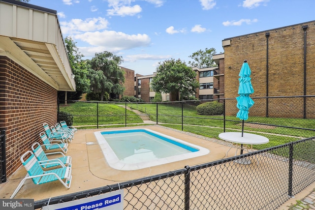 view of swimming pool featuring a lawn and fence