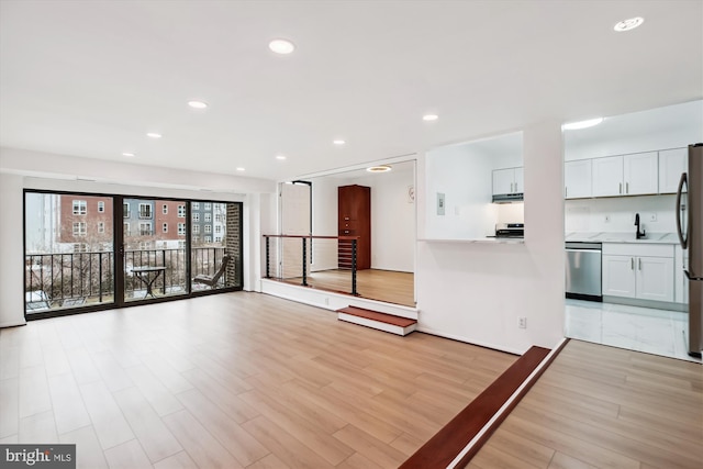 unfurnished living room with recessed lighting, a sink, and light wood finished floors