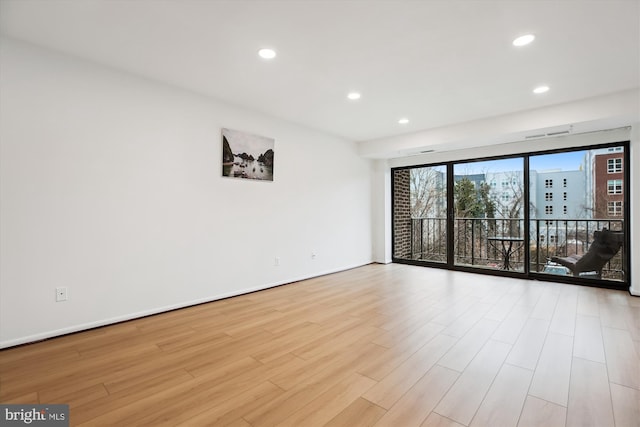 spare room with recessed lighting, wood finished floors, and baseboards