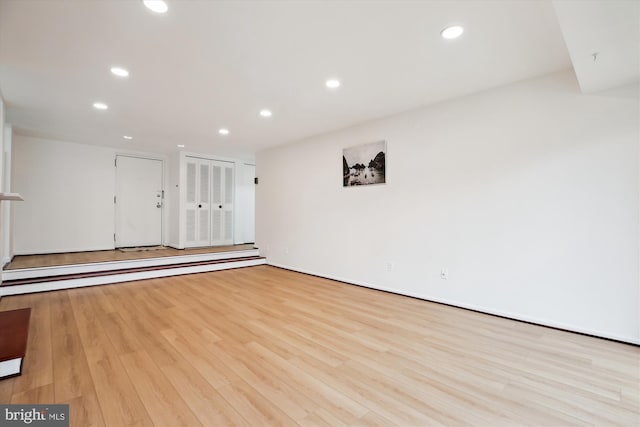 empty room with recessed lighting, wood finished floors, and a baseboard radiator