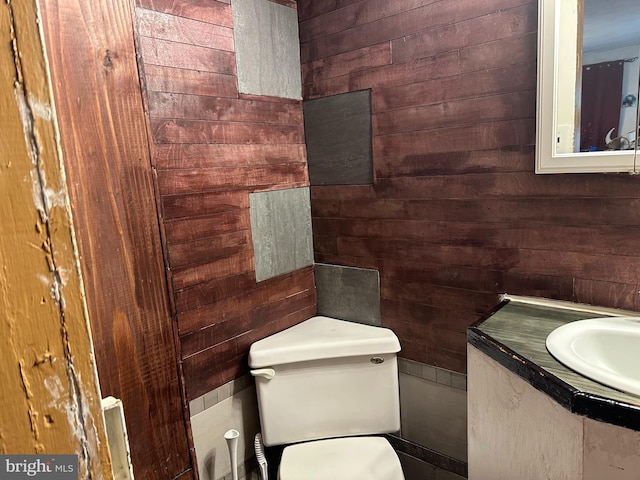 bathroom with wooden walls, toilet, and a sink