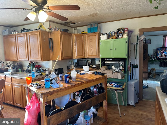 kitchen featuring ornamental molding, ceiling fan, light countertops, and light wood finished floors