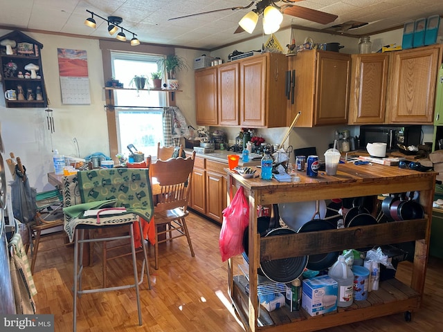 kitchen featuring light countertops, a ceiling fan, light wood finished floors, and black microwave