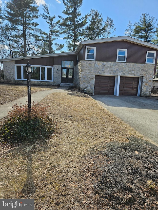 view of front facade with a garage, stone siding, and driveway