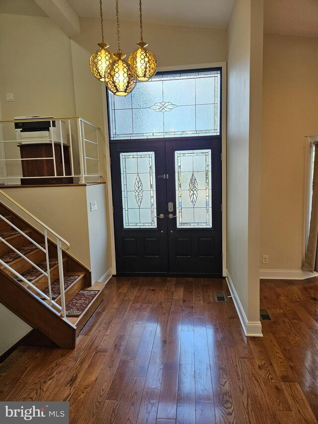 foyer entrance with visible vents, hardwood / wood-style floors, stairway, a high ceiling, and baseboards