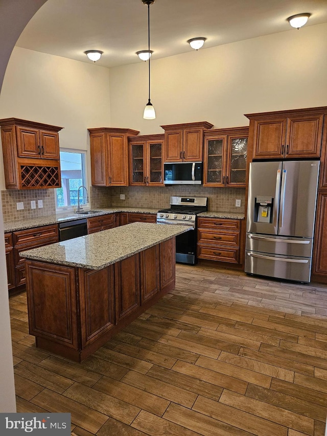 kitchen with decorative backsplash, appliances with stainless steel finishes, a towering ceiling, dark wood-style floors, and a sink