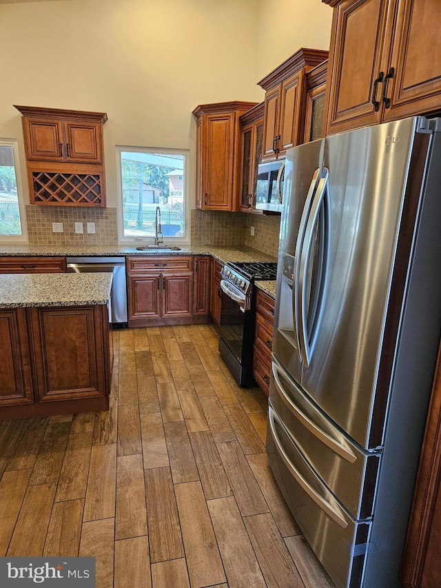 kitchen featuring backsplash, stainless steel appliances, wood finish floors, and a sink