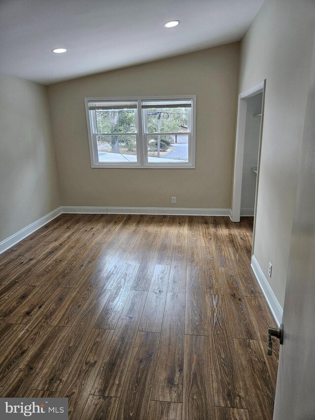 spare room featuring recessed lighting, baseboards, and dark wood-type flooring