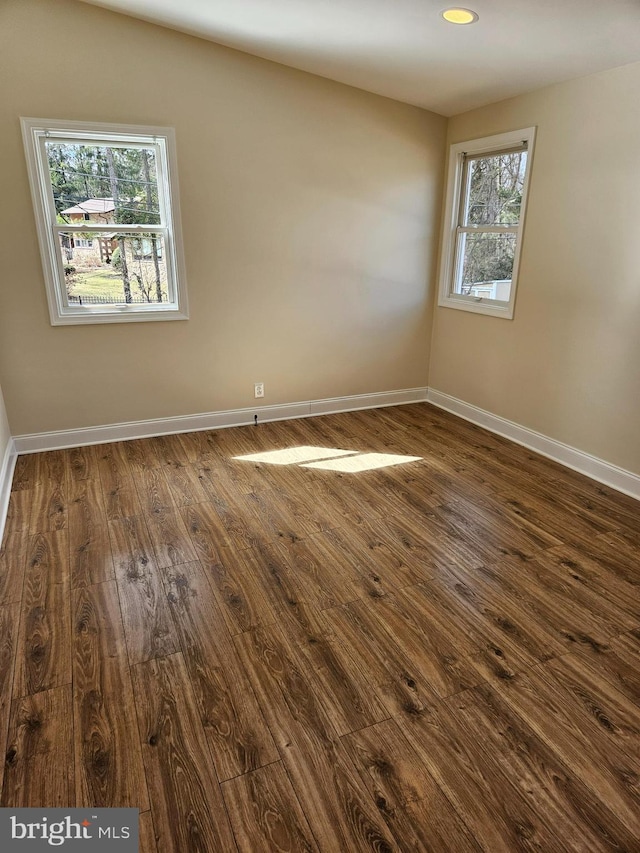 spare room with dark wood-type flooring, recessed lighting, and baseboards