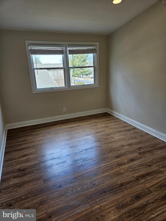 empty room with baseboards, a healthy amount of sunlight, and dark wood-style floors