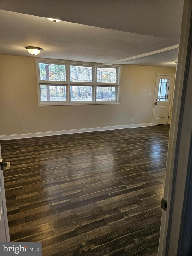 unfurnished room featuring baseboards and dark wood-style flooring