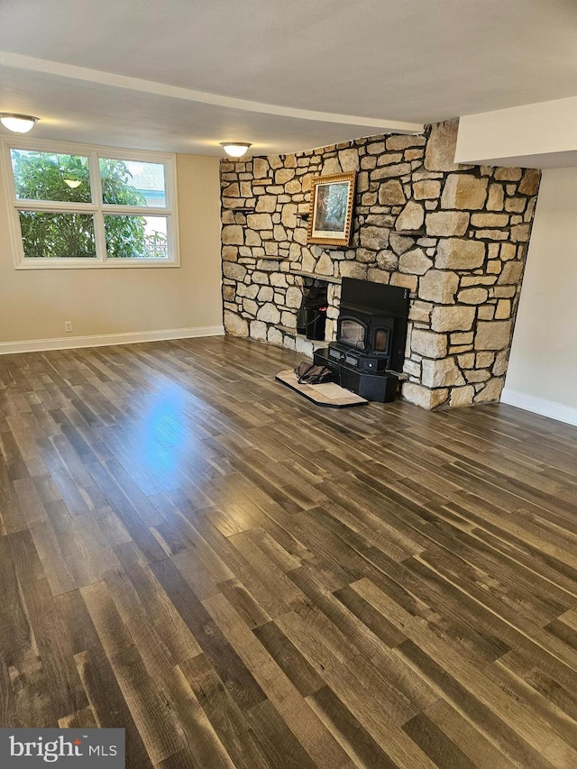 unfurnished living room featuring baseboards, wood finished floors, and a wood stove