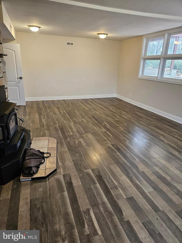 living room featuring visible vents, a wood stove, baseboards, and wood finished floors