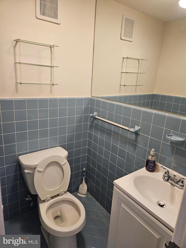 bathroom with visible vents, vanity, toilet, and tile walls