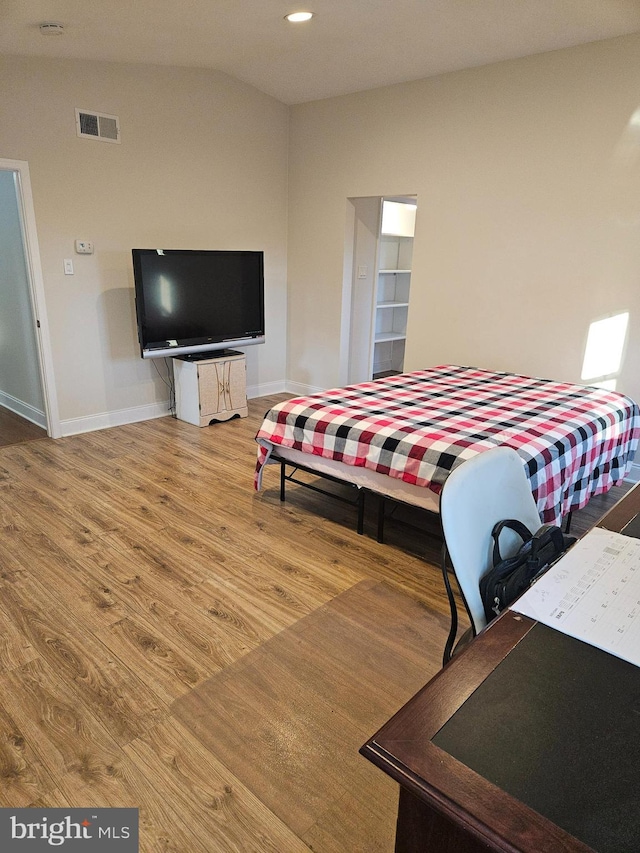 bedroom featuring visible vents, baseboards, lofted ceiling, and wood finished floors