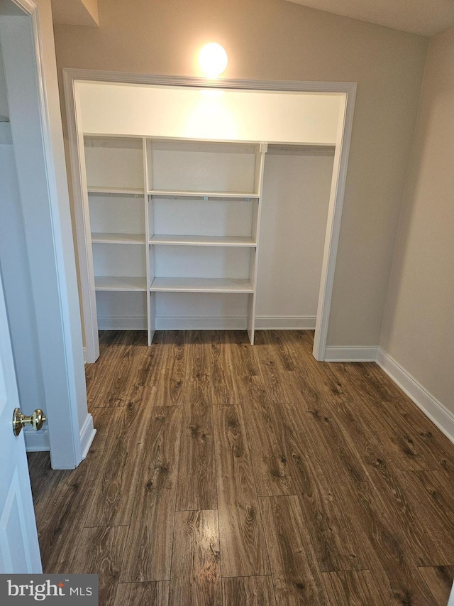 interior space featuring baseboards, dark wood-type flooring, and lofted ceiling