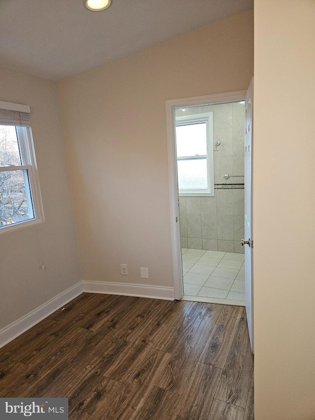 unfurnished room with plenty of natural light, wood finished floors, and baseboards