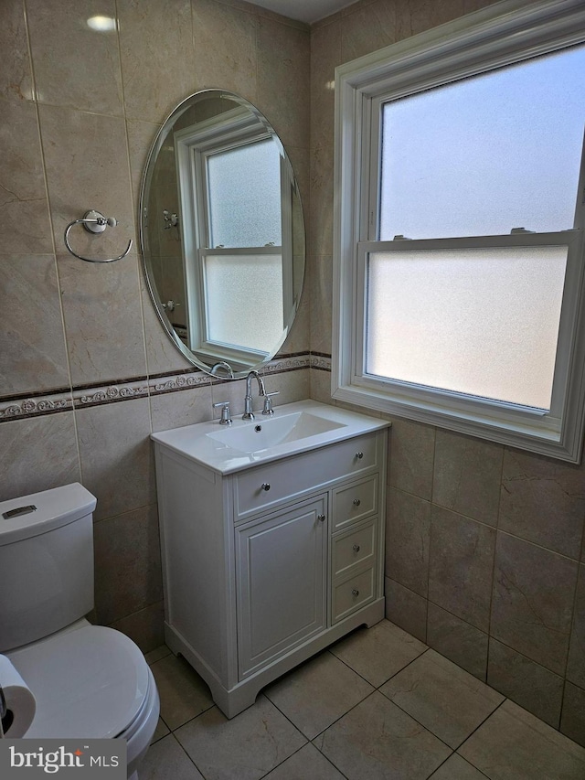 bathroom with tile patterned floors, toilet, tile walls, and vanity