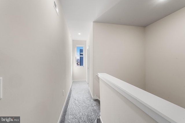 hallway featuring baseboards, light carpet, and an upstairs landing