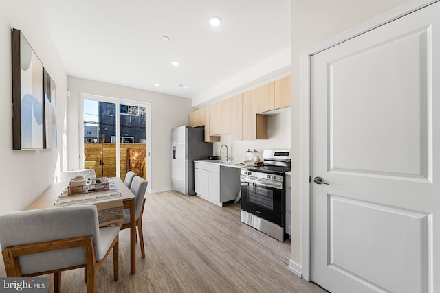 kitchen with baseboards, recessed lighting, stainless steel appliances, light countertops, and light wood-type flooring