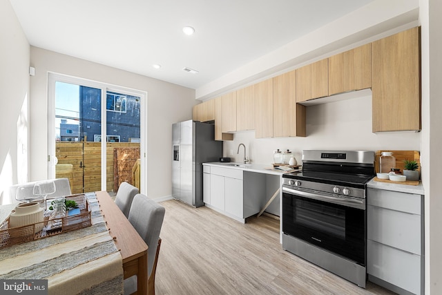 kitchen with light countertops, recessed lighting, appliances with stainless steel finishes, light wood-style floors, and a sink