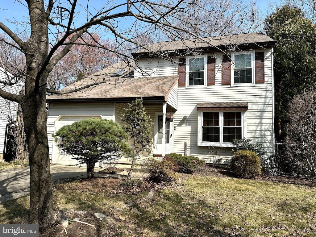 traditional home featuring a front lawn, a garage, and roof with shingles