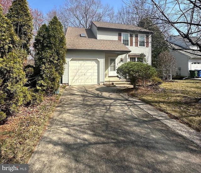 traditional-style home featuring concrete driveway, an attached garage, and a shingled roof