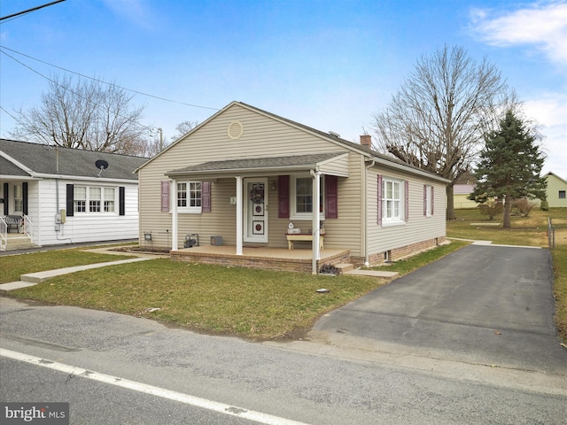 bungalow featuring a chimney, covered porch, and a front yard