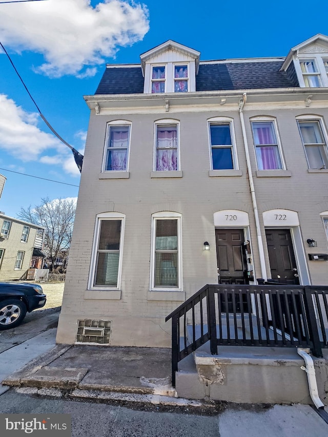 townhome / multi-family property with brick siding and a shingled roof