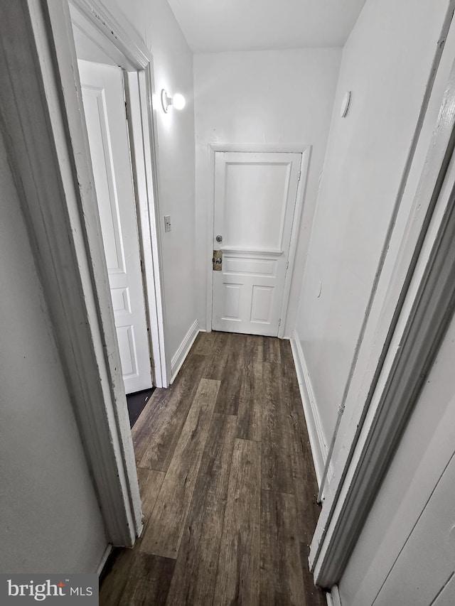 hallway featuring dark wood-style floors and baseboards