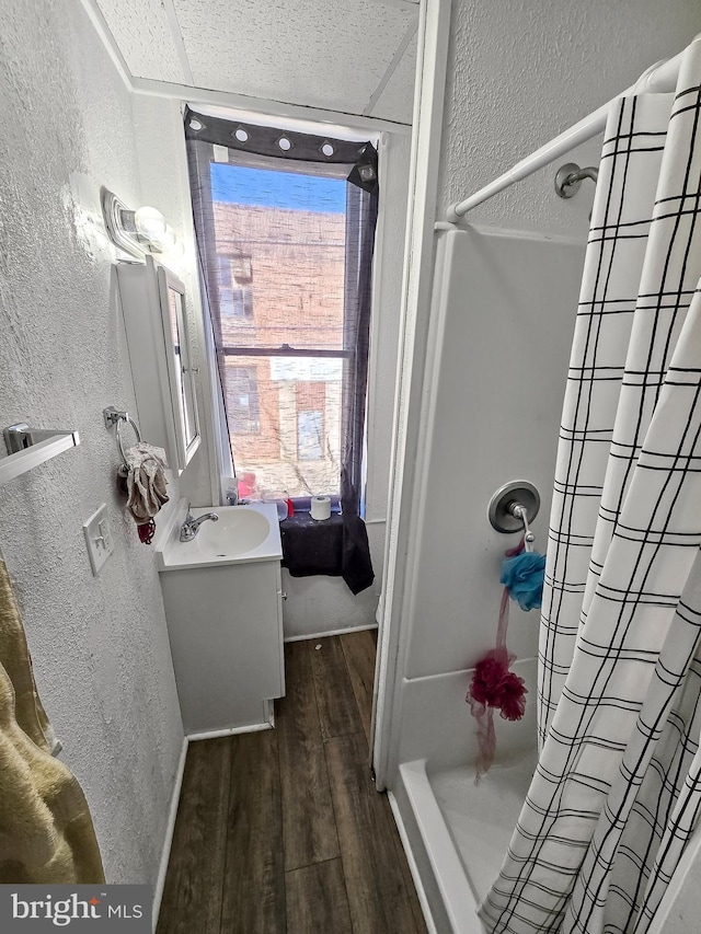 bathroom featuring wood finished floors, a shower with shower curtain, and a textured wall