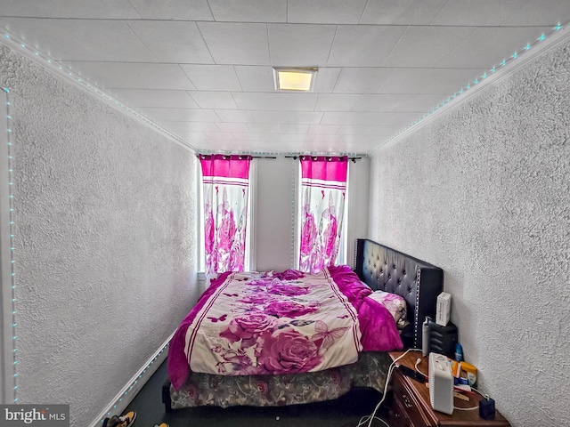 bedroom with ornamental molding and a textured wall