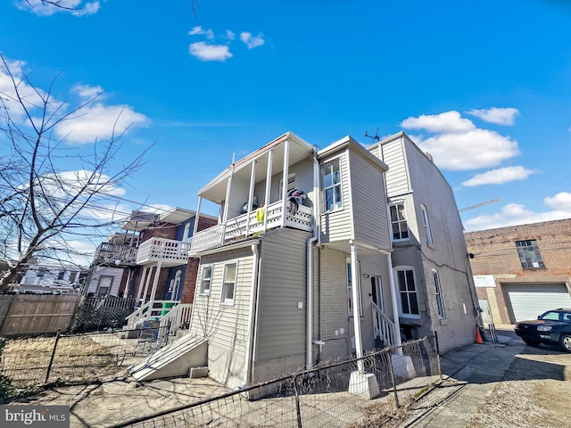 exterior space with a balcony, brick siding, and fence