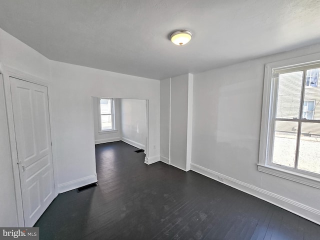 unfurnished room with visible vents, baseboards, and dark wood-type flooring