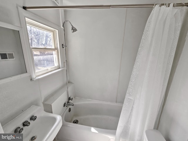 bathroom featuring toilet, visible vents, shower / bath combo, and a sink