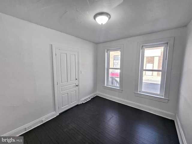 spare room with dark wood finished floors, visible vents, and baseboards