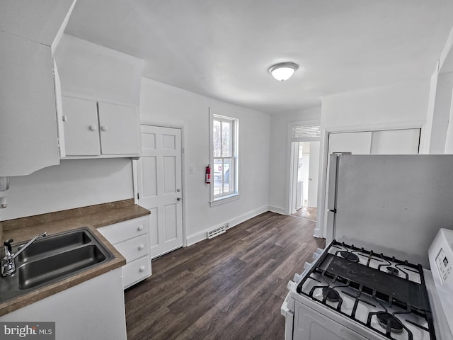 kitchen featuring visible vents, white gas range, freestanding refrigerator, white cabinets, and a sink